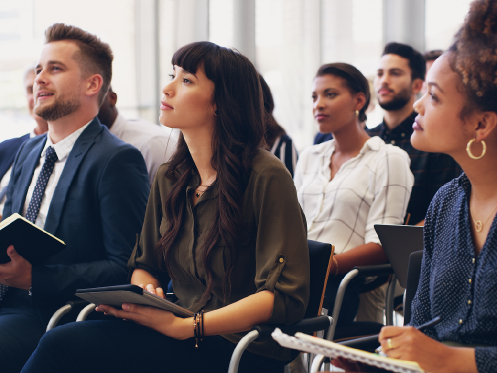 Colleagues in an audience taking notes