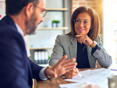 Woman smiling at male colleague looking at documents