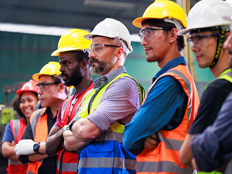 Construction workers standing in a line with their arms crossed