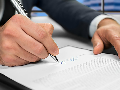 Mature businessman&#39;s hand signing document. Man signs paper beside window. New insurance policy. Official letter to a partner.