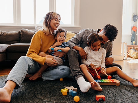 Young parents playing with their son and daughter in the living room. Mom and dad having fun with their children during playtime. Family of four spending some quality time together at home.