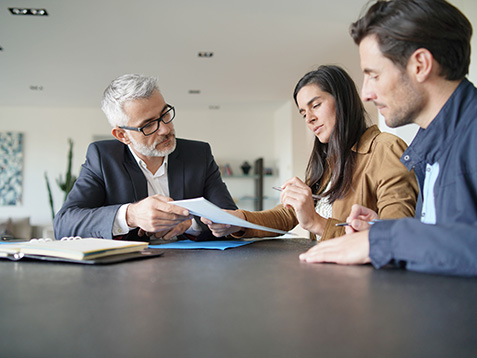  Attractive couple signing contract with real-estate agent in contemporary house                              