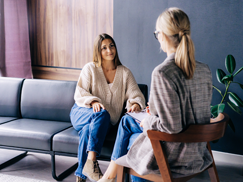 A smiling client is having a confidential conversation with a consultant psychologist.