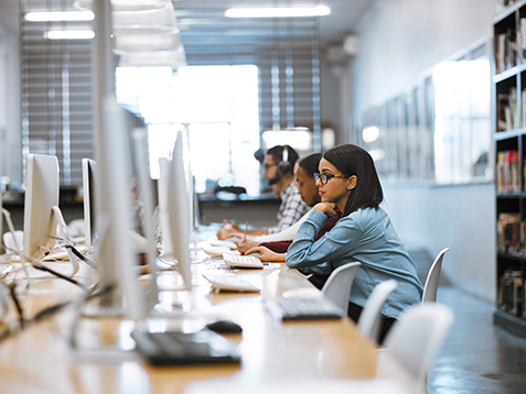 Shot of a group of university students working on computers in the library at campus
