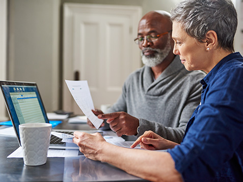 Laptop, documents and finance with a senior couple busy on a budget review in the home together. Accounting, taxes or investment planning with a mature man and woman looking at insurance or savings.