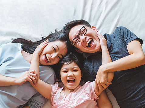 Happy Asian family laying on bed in bedroom with happy and smile, top view