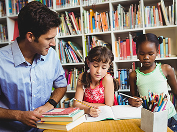 Dad reading to two kids in library