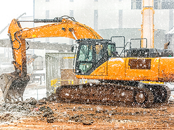 The excavator excavation at the cold weather also snowing in the construction site.