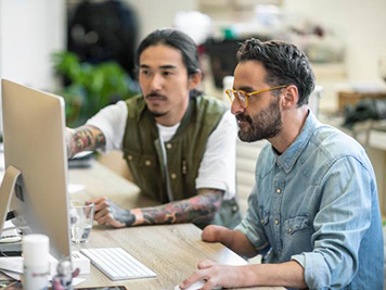 Male executives discussing over computer at desk