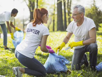 two volunteers picking up trash and putting in into a bag