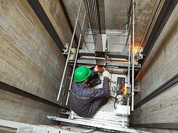 Elevator installation and maintenance. lift machinist worker adjusting elevator mechanism with spanners in shaft hoistway