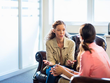 two women sitting in leather chairs having a conversation