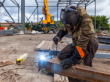 construction worker welding while wearing proper safety materials