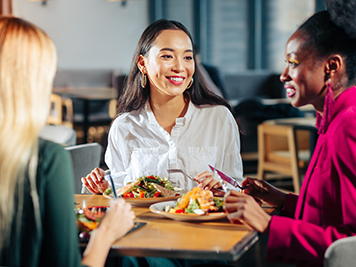 Three friends eating delicious salads in their favorite restaurant