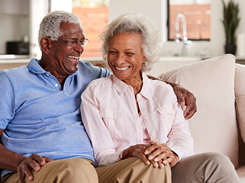 Loving Senior Couple Sitting On Sofa At Home And Laughing Together 