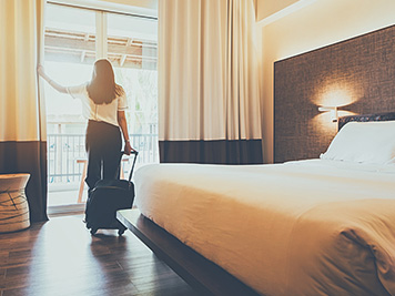 Asian women are staying in a hotel room. Open the curtain in the room Along with carrying luggage.Concept of people be comfortable to travel.