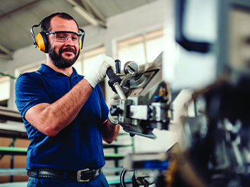 man wearing safety goggles and ear muffs using machinery 