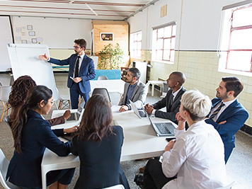 Confident business team working at office. Group of workers sitting at table and listening speaker. Business meeting concept