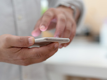 Close up view of male designer using blank screen smartphone while standing in simple working place