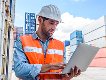 Male engineer wearing safety gear, using computer