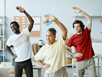 Diverse group of young people doing stretching exercises during warm up break in office