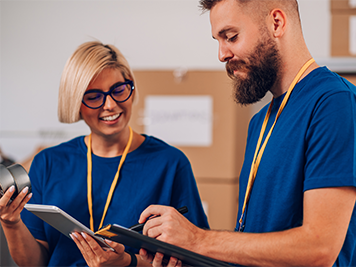 Portrait of a volunteers working in community charity donation center. Volunteers putting clothes and other supplies in donation boxes. Focus on a volunteer or a social worker man making notes.