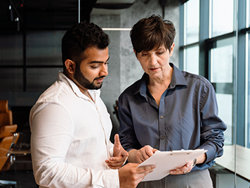 Positive multiethnic colleagues checking documents and talking in office