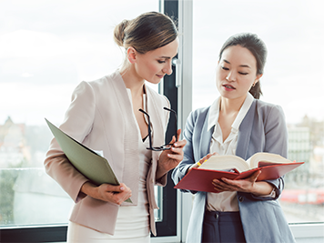 two business women discussing what is in a corporate book