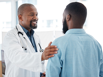 Doctor, black man and touch shoulder of patient for support, comfort and empathy in hospital. Healthcare, consultation and happy medical professional talking, good news or kindness with mature person.