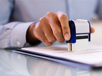 A hand using a stamp on a document