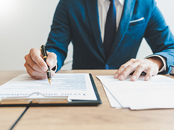 Man wearing a suit signing documents at a table