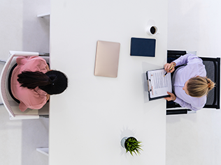 Two young business women in meeting at office table for job application and business agreement. Recruitment and human resources concept.