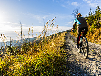 Mountain biking woman riding on bike in autumn mountains forest landscape. Woman cycling MTB flow trail track. Outdoor sport activity.