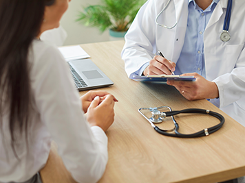 Close up shot of a doctor or nurse writing a prescription for the patient during a medical consultation in the hospital. Healthcare professional support and care in a clinical setting.