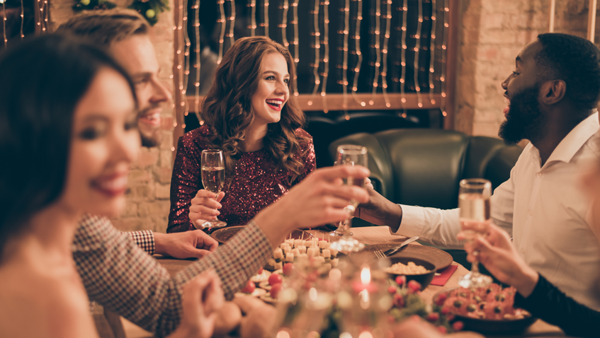 A Zebra named Ed being airlifted via helicopter in a dark mesh sack flying above the trees against blue skies.  